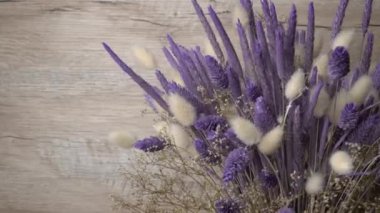 Dried flowers in purple hues rotate close-up. Beautiful lagurus, falyaris and spikelets in a beautiful bouquet. Gift bouquet of dried flowers.