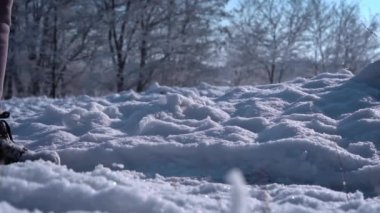 Feet in winter boots walk on white and fluffy snow in slow mo. Walking along the winter paths in sunny weather. A man walks through the snow in the forest.