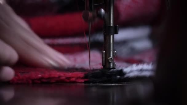 缝纫机的针脚穿透了面料的特写 一个戴眼镜的老妇人在一台旧缝纫机上缝制 女裁缝把机器做的缝在红色的织物上 — 图库视频影像