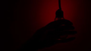 Light bulb turns on and goes out at the touch of a persons hand in the dark. Slow turning on and off of a tungsten light bulb. Filament of a blinking vintage light bulb. Energy, electricity, light