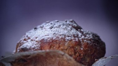 Powdered sugar is sprinkled on appetizing chocolate muffin close-up. Delicious dessert slowly sprinkled with powder. Ready to eat cupcake with crispy crust. Dessert decorated with dark chocolate.
