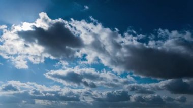 Beyaz kabarık bulutlar mavi gündüz vakti gökyüzünde yavaşça süzülür. Güzel gökyüzü hareket ediyor. Kar beyazı bulutlar yana doğru hareket ediyor..