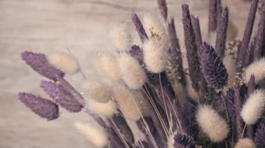 Dried flowers in purple hues rotate close-up. Beautiful lagurus, falyaris and spikelets in a beautiful bouquet. Gift bouquet of dried flowers.