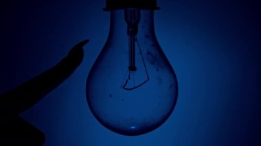 Light bulb turns on and goes out at the touch of a persons hand in the dark. Slow turning on and off of a tungsten light bulb. Filament of a blinking vintage light bulb. Energy, electricity, light