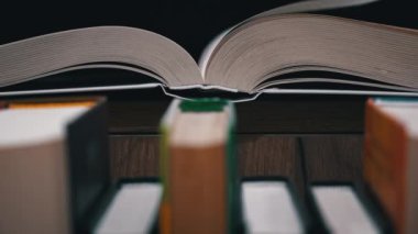 Young girl reads a book on the background of a shelf with books. Library bookshelves background stack of books. The pages of the book are turning. Reading scientific literature surrounded by books.