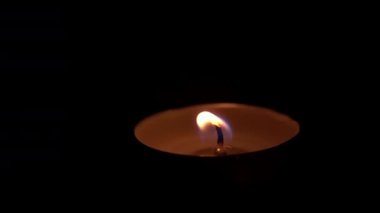 Paraffin candle burns in the dark with a yellow flame. A large fire in a wax candle burns yellow. There is no light in the house, heat from a candle. Poverty, war, a moment of silence.