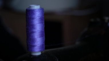 Makaradaki iplik dikiş makinesinde dikiş dikmek için bir bobbin üzerine sarılmış. Terzilik kavramı, kadın hobisi. Modern dikiş işi. Terzi dikiş atölyesinde kumaş dikiyor. Dikiş kumaşı süreci