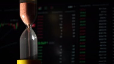 Hourglass is falling on background of a crypto exchange close-up. Time is money. With every minute, cryptocurrency rises or falls. Eth and btc quotes on stock exchange. Stock market chart.