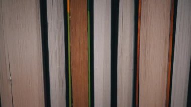 Young girl chooses a book on a shelf with books. Library bookshelves background stack of books. The pages of the book are turning. Reading scientific literature surrounded by books.