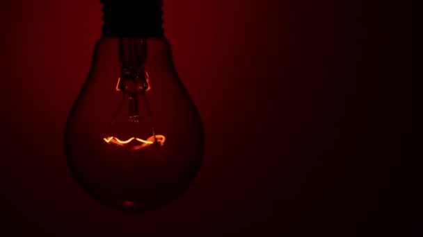 Light Bulb Lights Goes Out Red Background Dark Slow Turning — Vídeo de stock
