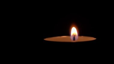 Paraffin candle burns in the dark with a yellow flame. A large fire in a wax candle burns yellow. There is no light in the house, heat from a candle. Poverty, war, a moment of silence.