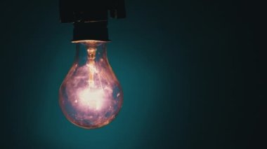 Karanlıkta mavi bir fonda ampul yanar. Tungsten ampulünü yavaşça kapat. Yanıp sönen eski bir ampulün filamanı. Enerji, elektrik, ışık, yaşam. Yenilik kavramı.