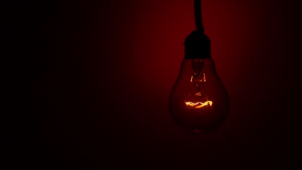 Light Bulb Flashes Red Background Dark Slow Turning Tungsten Light – Stock-video