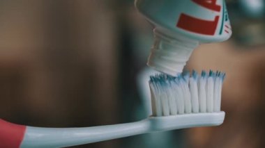 Toothpaste climbs out of the tube onto the toothbrush close-up. Apply toothpaste to the brush. Morning brushing of teeth. Take care of your teeth. Daily hygiene.