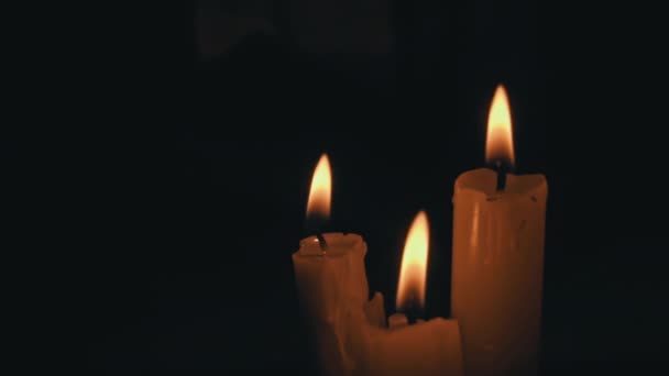 白色石蜡蜡烛 黄色的色调在黑色的背景上燃烧 一根蜡蜡烛一动不动地燃烧着 发出火光 — 图库视频影像
