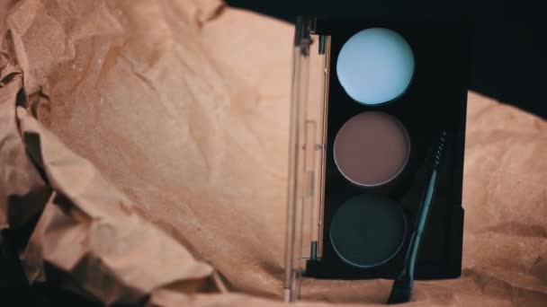 クラフトの背景に眉の影の渦 肉色の新しい原始的な化粧品 化粧パレットセット プロ仕様マルチカラーアイシャドウパレットクローズアップ — ストック動画