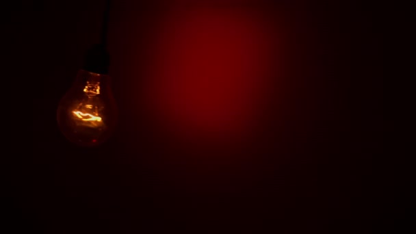 Light Bulb Staggers Red Background Dark Slow Turning Tungsten Light – Stock-video