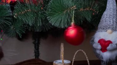 Gri safkan kedi yılbaşı oyuncaklarıyla Noel ağacında oynuyor. Aktif bir hayvan Noel ağacı oyuncağının yanındaki hareketleri takip ediyor. Noel ağacının altında şakacı bir kedi oturuyor.
