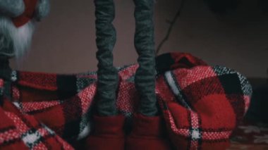 New Years Scandinavian gnome stands near the Christmas tree. A red Christmas elf decorates houses on New Years Eve.