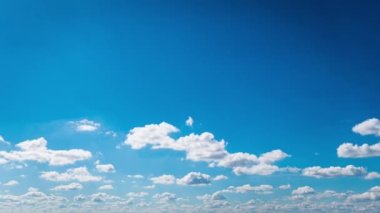 Beyaz kabarık bulutlar mavi gündüz vakti gökyüzünde yavaşça süzülür. Güzel gökyüzü hareket ediyor. Kar beyazı bulutlar yana doğru hareket ediyor..