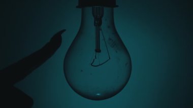 Ampul, karanlıkta bir insan elinin dokunuşuyla açılıp söner. Tungsten ampulü yavaş yavaş açıp kapanıyor. Yanıp sönen eski bir ampulün filamanı. Enerji, elektrik, ışık