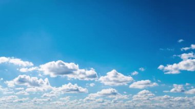 White fluffy clouds slowly float through the blue daytime sky timelapse. Beautiful skies are moving. Airy snow-white clouds move to the side.