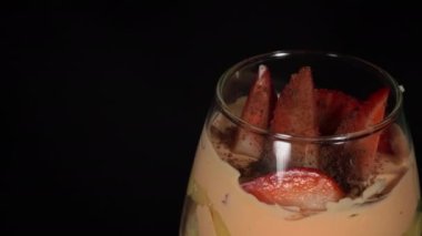 Çilekli küçük bir cam parçası güzel bir dekor ile dönüyor. Pasta şefi bayram için meyve süslemesi yapıyor. Farklı katmanlı bir bardakta kek. Lezzetli tatlı tabakta dönüyor..
