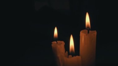 Siyah arka planda sarı renkli beyaz parafin mumlar. Bir mum hareketsiz yanar ve ateş yayar..