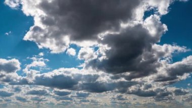 White fluffy clouds slowly float through the blue daytime sky timelapse. Beautiful skies are moving. Airy snow-white clouds move to the side.