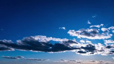 White fluffy clouds slowly float through the blue daytime sky timelapse. Beautiful skies are moving. Airy snow-white clouds move to the side.