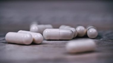 Beyaz hap kapsülleri yavaş çekimde yüzeye çıkar. İlaç kapsülleri. Sağlık hizmetleri ve ilaç üretimi kavramı. Kendimi kötü hissediyorum, hastane..