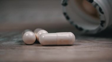Beyaz hap kapsülleri yavaş çekimde yüzeye çıkar. İlaç kapsülleri. Sağlık hizmetleri ve ilaç üretimi kavramı. Kendimi kötü hissediyorum, hastane..
