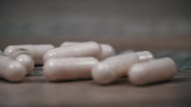 Beyaz hap kapsülleri yavaş çekimde yüzeye çıkar. İlaç kapsülleri. Sağlık hizmetleri ve ilaç üretimi kavramı. Kendimi kötü hissediyorum, hastane..