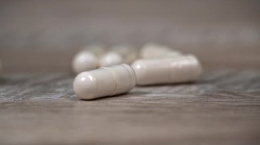 Beyaz hap kapsülleri yavaş çekimde yüzeye çıkar. İlaç kapsülleri. Sağlık hizmetleri ve ilaç üretimi kavramı. Kendimi kötü hissediyorum, hastane..