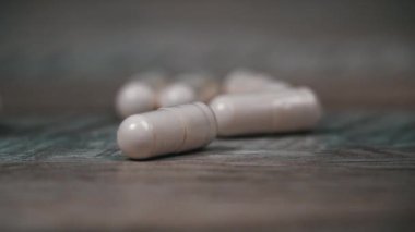 Beyaz hap kapsülleri yavaş çekimde yüzeye çıkar. İlaç kapsülleri. Sağlık hizmetleri ve ilaç üretimi kavramı. Kendimi kötü hissediyorum, hastane..