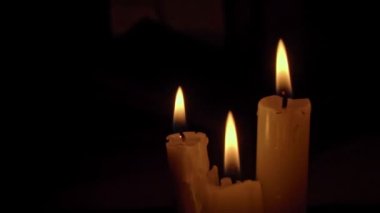 Siyah arka planda sarı renkli beyaz parafin mumlar. Bir mum hareketsiz yanar ve ateş yayar..