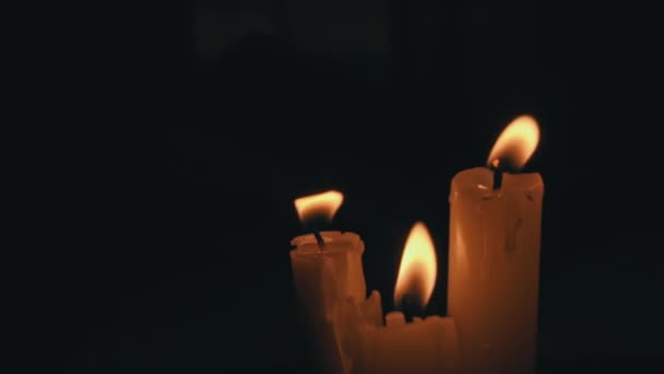 白色石蜡蜡烛 黄色的色调在黑色的背景上燃烧 一根蜡蜡烛一动不动地燃烧着 发出火光 — 图库视频影像