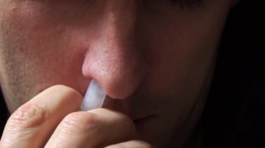 Adam kırmızı burnuna özel bir sprey sıkar. Hasta bir insan burnunun akmasından muzdarip. Viral enfeksiyon. Sağlık hizmetleri. Ev tedavisi.