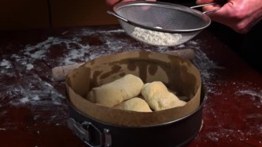 Un, bir elek vasıtasıyla bir fırın kabının içindeki biçimli somuna dökülür. Ev yapımı un kekleri. Yapışkan hamuru ellerinle yoğur. Organik taze ekmek. Baker fırında yemek pişiriyor..
