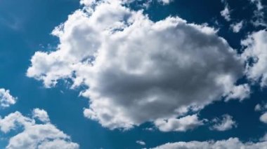 Beyaz kabarık bulutlar mavi gündüz vakti gökyüzünde yavaşça süzülür. Güzel gökyüzü hareket ediyor. Kar beyazı bulutlar yana doğru hareket ediyor..