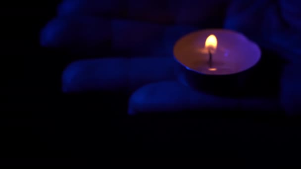 在蓝色的灯光下 人们手握一支蜡烛 石蜡蜡蜡烛在黑暗中与黄色的火焰一起燃烧 房子里没有灯 是蜡烛发出的热 沉默的时刻 — 图库视频影像