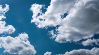 Beyaz kabarık bulutlar mavi gündüz vakti gökyüzünde yavaşça süzülür. Güzel gökyüzü hareket ediyor. Kar beyazı bulutlar yana doğru hareket ediyor..