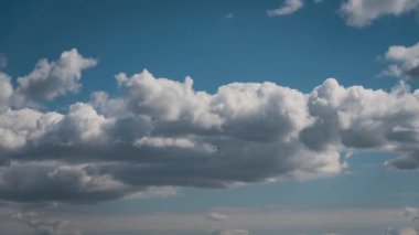 Beyaz kabarık bulutlar mavi gündüz vakti gökyüzünde yavaşça süzülür. Güzel gökyüzü hareket ediyor. Kar beyazı bulutlar yana doğru hareket ediyor..