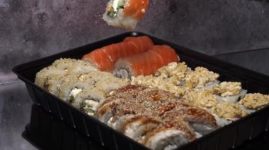 Sushi dürümleri yakın plan suşi için yemek çubuklarıyla alınır. Bir restoranda Japon mutfağı suşisi. Somon ve sebzeli suşi. Japon restoran menüsü. Yan görünüm.