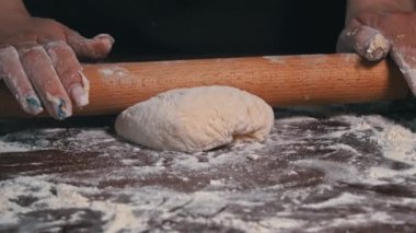 Kadın eli merdaneyle hamuru yuvarlıyor. Ev yapımı un kekleri. Yapışkan hamuru ellerin ağır çekimde diz. Organik taze ekmek. Baker fırında yemek pişiriyor..