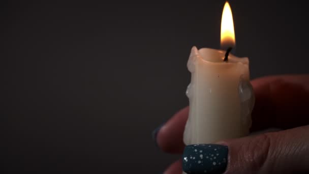 在黑暗的特写中 曼斯的手拿着一支蜡烛 石蜡蜡蜡烛在黑暗中燃烧着黄色的火焰 房子里没有灯 是蜡烛发出的热 沉默的时刻 — 图库视频影像