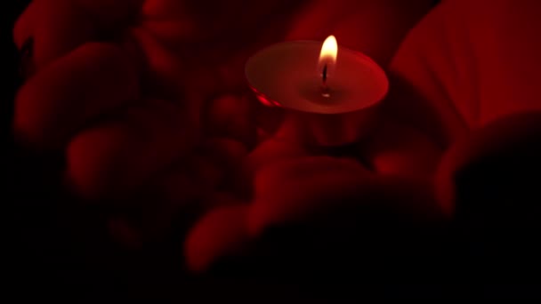 在红色灯火的特写下 人们手握一支蜡烛 石蜡蜡蜡烛在黑暗中与黄色的火焰一起燃烧 房子里没有灯 是蜡烛发出的热 沉默的时刻 — 图库视频影像