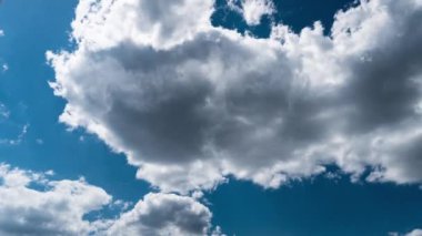 Beyaz kabarık bulutlar mavi gündüz vakti gökyüzünde yavaşça süzülür. Güzel gökyüzü hareket ediyor. Kar beyazı bulutlar yana doğru hareket ediyor..