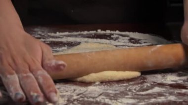 Kadın eli merdaneyle hamuru yuvarlıyor. Ev yapımı un kekleri. Yapışkan hamuru ellerin ağır çekimde diz. Organik taze ekmek. Baker fırında yemek pişiriyor..