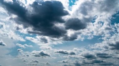 White fluffy clouds slowly float through the blue daytime sky timelapse. Beautiful skies are moving. Airy snow-white clouds move to the side.